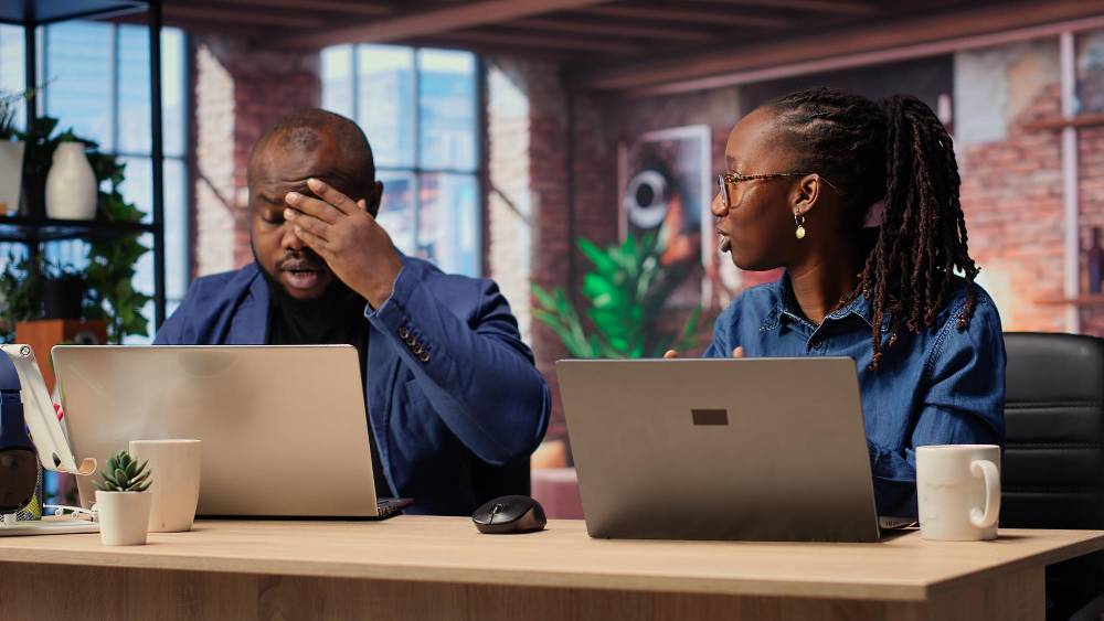 Photo of two HR workers at a desk in front of their laptops