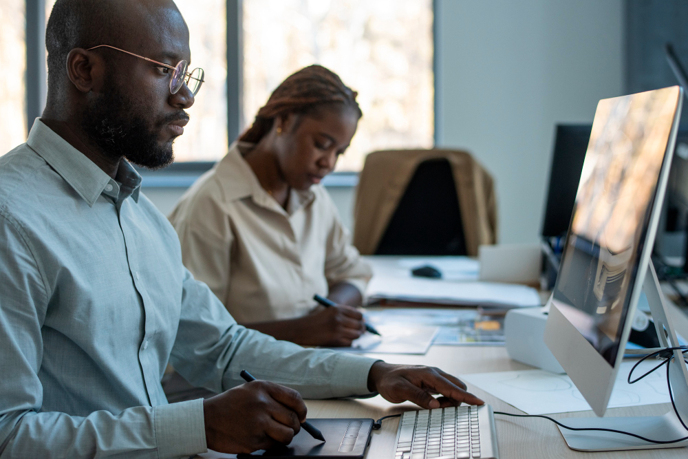 Two workers interacting with HR management software (HRIS) in Ghana